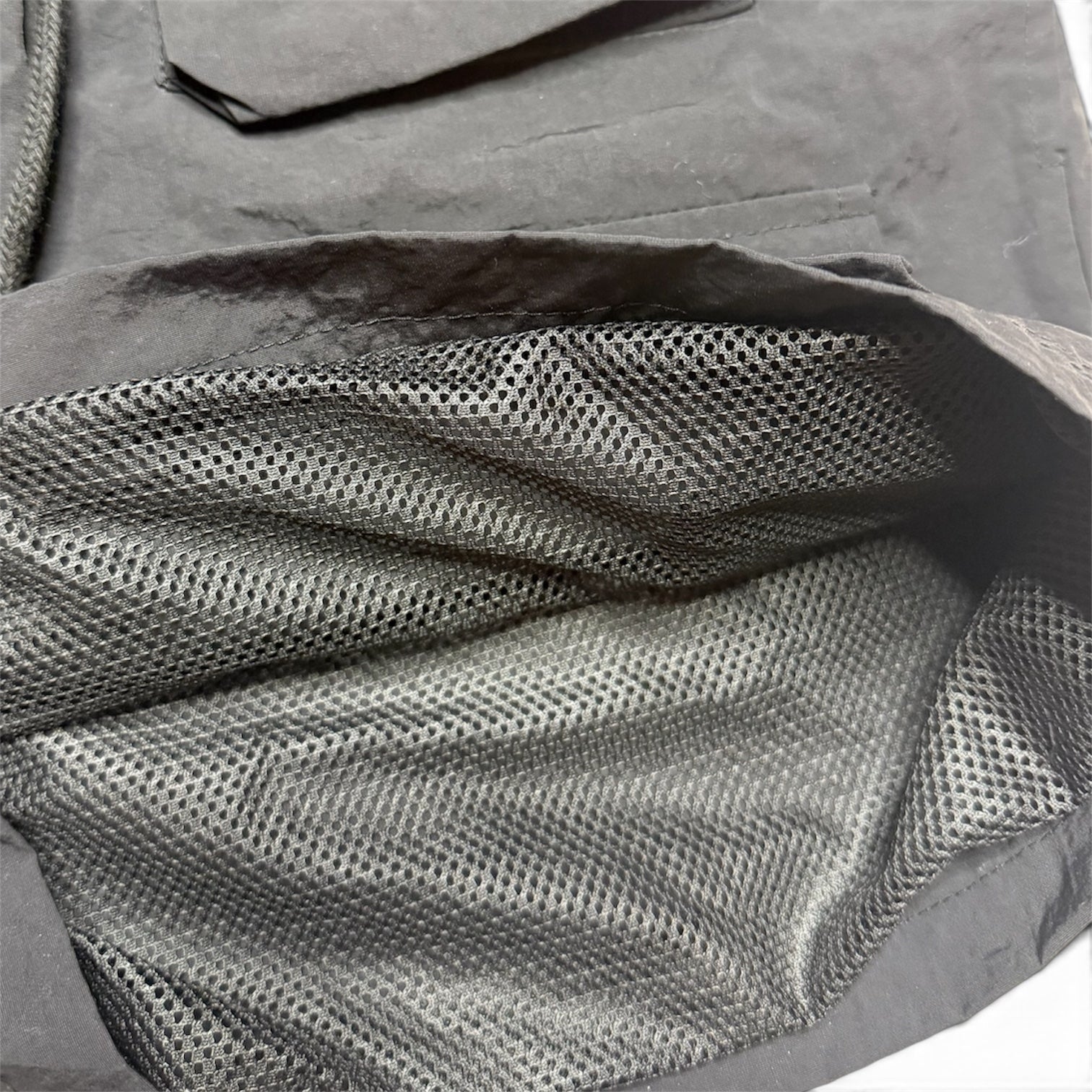 Close-up of a dark gray mesh fabric interior with a stitched edge and textured material.