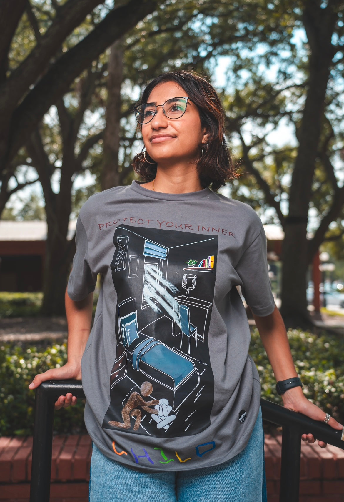 Woman wearing protect your inner child tees to show flattering fit. Gender neutral original artwork tee. Overcoming depression, hugging yourself as a child. Protecting your inner child tee. Gray Screenprinted tee. original artwork. Unisex tees. Tighter neckline crewneck. 