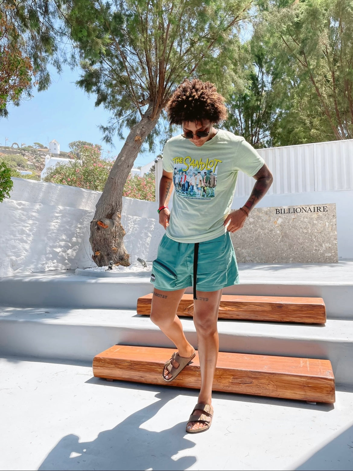 Androgynous or masculine look in merakitay cargo shorts. Woman in cargo shorts. Gender neutral cargo shorts. Teal or blue in color, embroidered logo, adjustable waistband, includes belt, and has six (6) pockets. Mid-thigh length, 3-5 inch inseam. Unisex shorts.